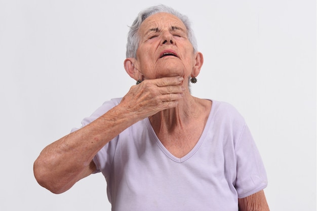 Mujer mayor con el cuello en el fondo blanco