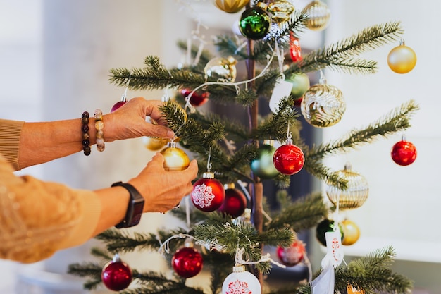 Mujer mayor decorando un árbol de Navidad en casa