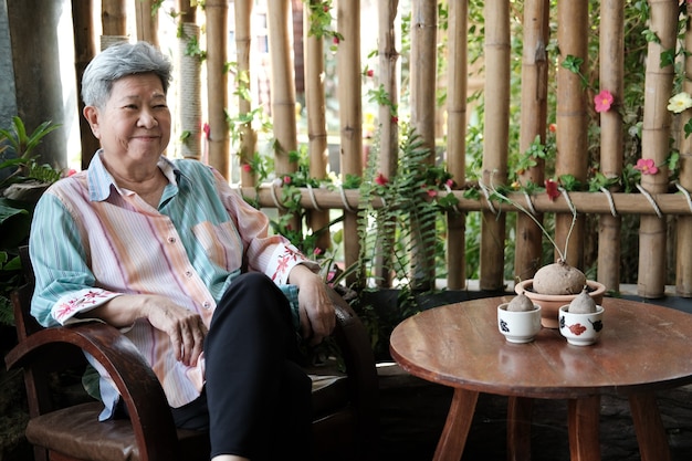 Mujer mayor descansando en casa. anciana asiática sentada en una silla. estilo de vida de ocio senior