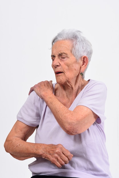 Mujer mayor con dolor en hombro en el fondo blanco