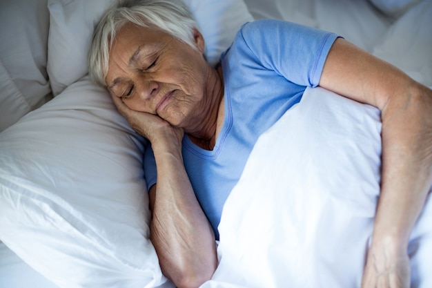 Mujer mayor durmiendo en el dormitorio en casa