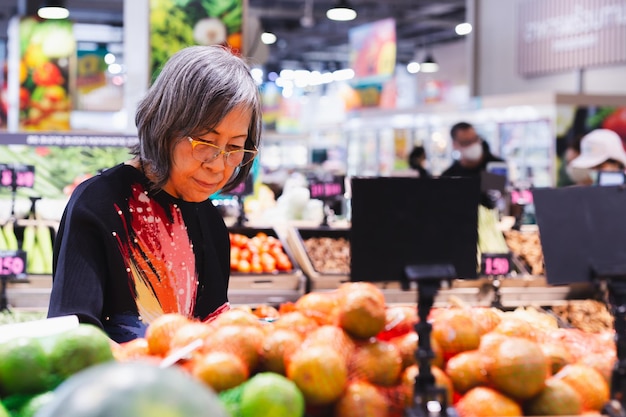 Mujer mayor eligiendo frutas y verduras en