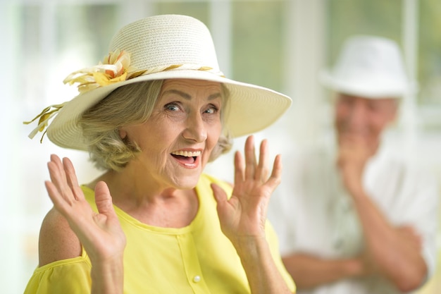Mujer mayor emocionada con sombrero mirando a la cámara