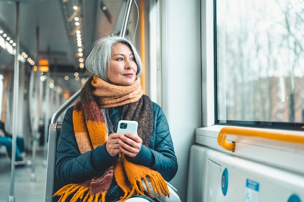 Mujer mayor envía un mensaje con un teléfono móvil en un tren