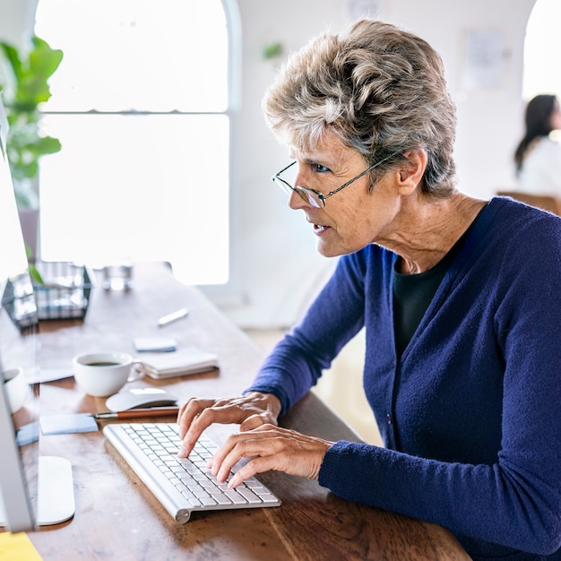 Mujer mayor escribiendo en un teclado de computadora