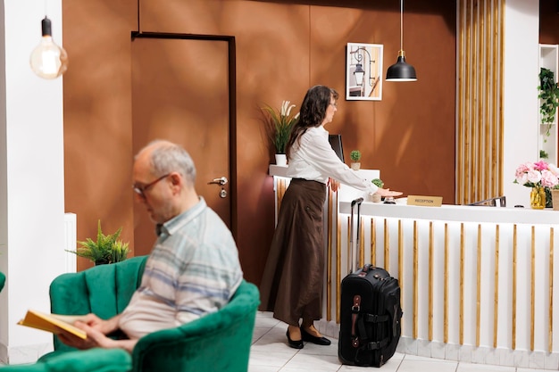 Una mujer mayor espera en la recepción del hotel.