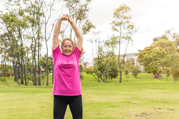 Mujer mayor estirando los brazos y haciendo ejercicio en el parque