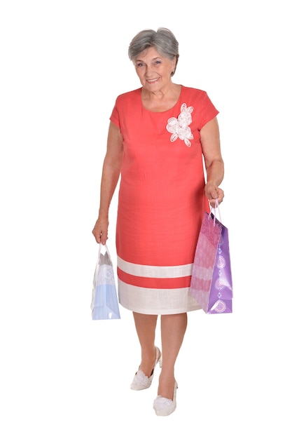 Mujer mayor feliz con bolsas de la compra sobre un fondo blanco.