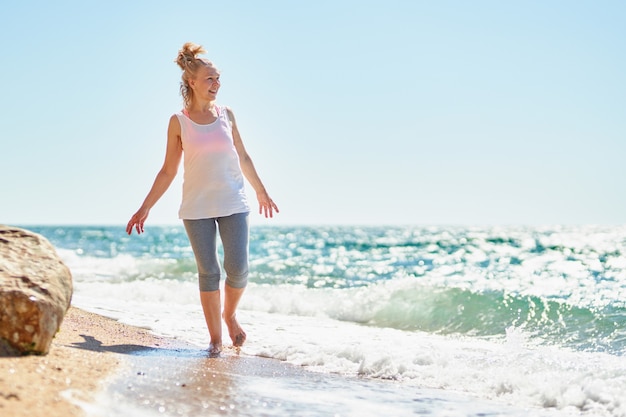 Mujer mayor feliz camina por el mar.