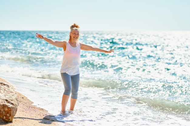 Mujer mayor feliz camina por el mar.