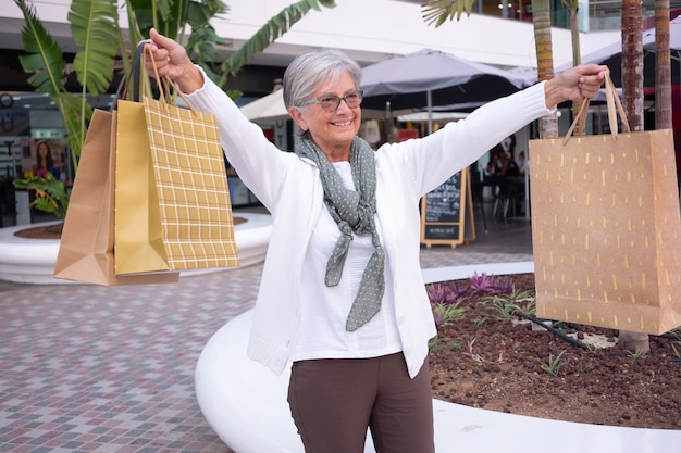 Mujer mayor feliz en compras. Mujer madura con bolsas de compras disfrutando de compras. Consumismo, compras, concepto de estilo de vida.