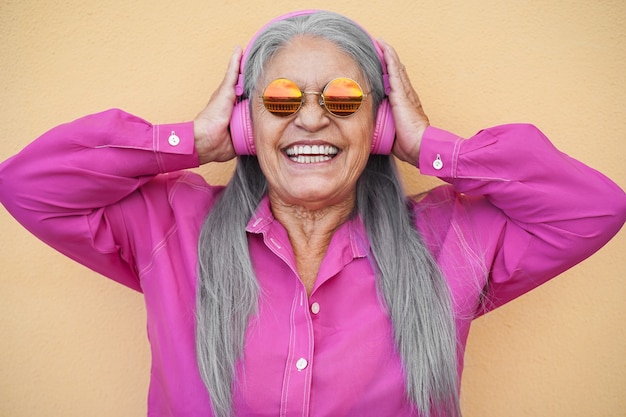 Mujer mayor feliz escuchando música de lista de reproducción con auriculares