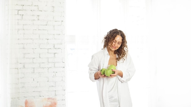 Mujer mayor feliz con pelo rizado con manzanas verdes. Dieta. Estilo de vida saludable.