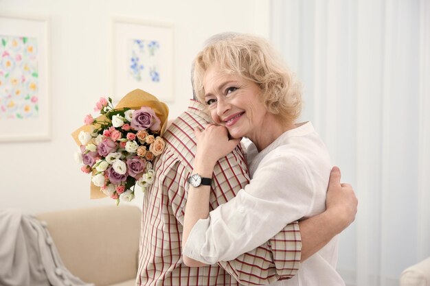 Mujer mayor feliz con ramo de flores abrazando a su marido