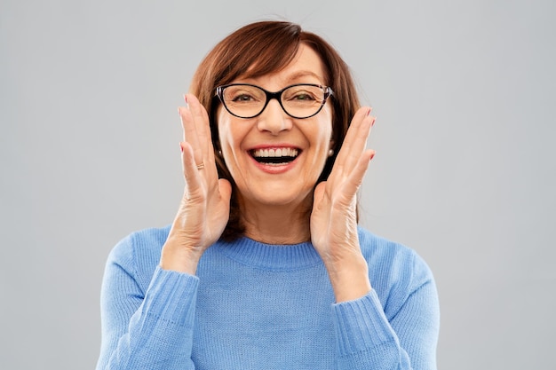 mujer mayor con gafas llamando sobre gris