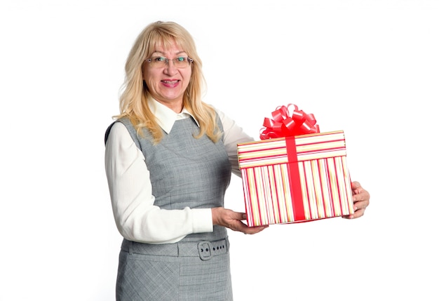 Mujer mayor con gran caja de regalo en la mano sobre un fondo claro.