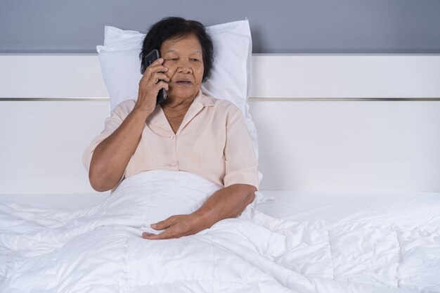 mujer mayor hablando por teléfono móvil en la cama