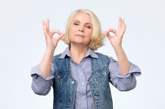 Mujer mayor haciendo gesto de meditación con los dedos