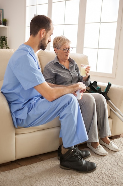 Mujer mayor en el hogar de ancianos tomando su medicina. Doctor masculino.