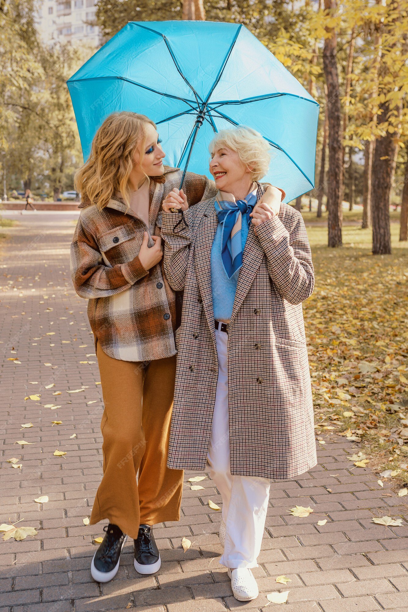 Mujer mayor, con, joven, hija, aire libre, debajo, paraguas azul, otoño, parque Foto Premium