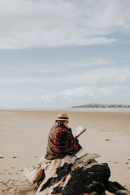 Mujer mayor jubilada leyendo un libro en la playa