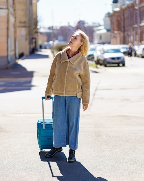 Mujer mayor con maleta azul viajando sola después de la jubilación