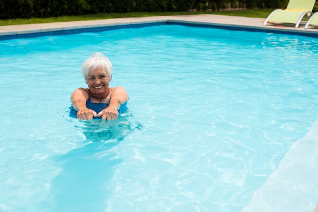 Mujer mayor nadando en la piscina en un día soleado