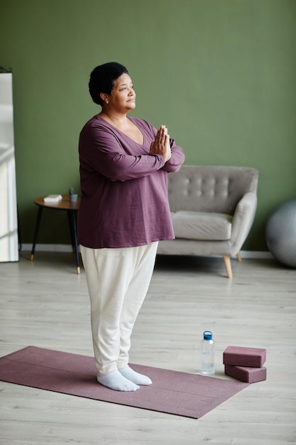 Mujer mayor negra meditando en casa