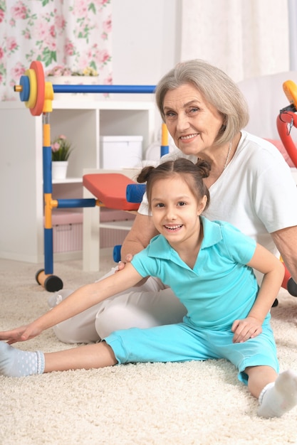 Mujer mayor y nieta haciendo ejercicio en casa