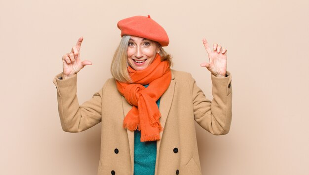 Mujer mayor o de mediana edad enmarcando o delineando su propia sonrisa con ambas manos, luciendo positivo y feliz, concepto de bienestar