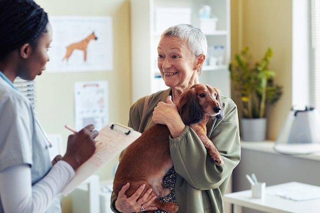 Mujer mayor con perro en clínica veterinaria