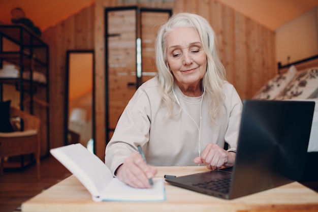 Mujer mayor con portátil sentado a la mesa y hablando en la tienda de campaña glamping concepto de estilo de vida moderno de vacaciones