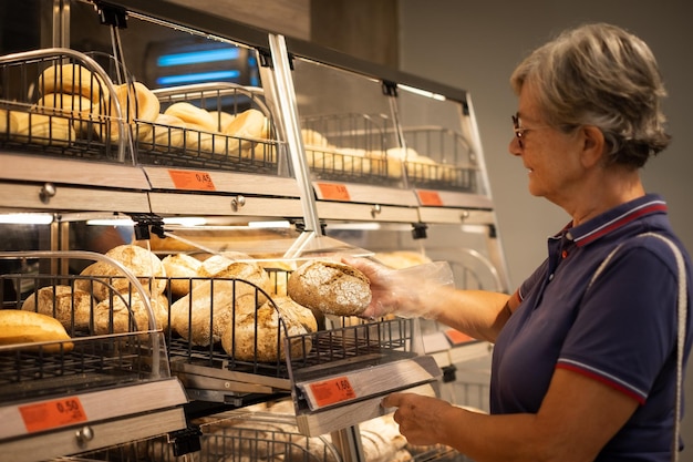 Mujer mayor que elige un pan de cereal en el supermercado