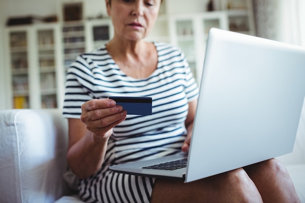 Mujer mayor que hace compras en línea en la computadora portátil