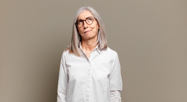 Foto mujer mayor que se siente confundida y dudosa, preguntándose o tratando de elegir o tomar una decisión