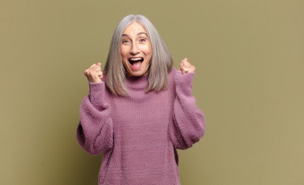 Mujer mayor que se siente sorprendida, emocionada y feliz, riendo y celebrando el éxito, diciendo ¡guau!