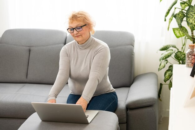 Mujer mayor que trabaja en su computadora portátil, anciana.