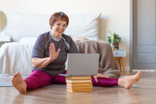 Mujer mayor con reunión en línea con un entrenador en línea antes de un entrenamiento de Pilates. El concepto de un estilo de vida activo y saludable en la vejez.