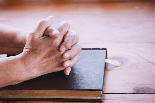 Una mujer mayor reza con una Santa Biblia