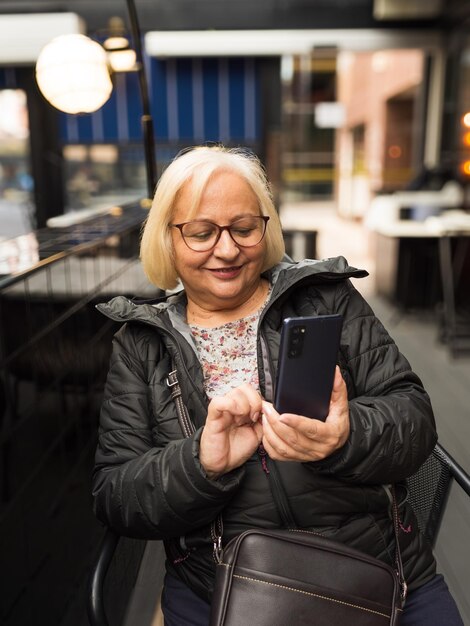 Una mujer mayor rubia feliz mirando su teléfono celular.