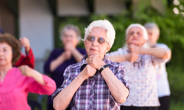 mujer mayor sana haciendo ejercicio con amigos frente a la casa de retiro