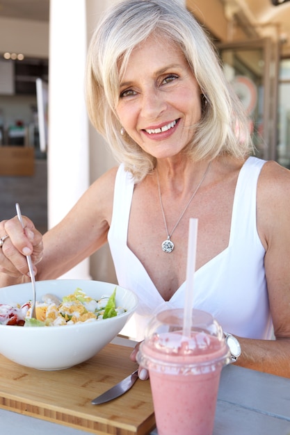 Mujer mayor sana que come en el restaurante al aire libre