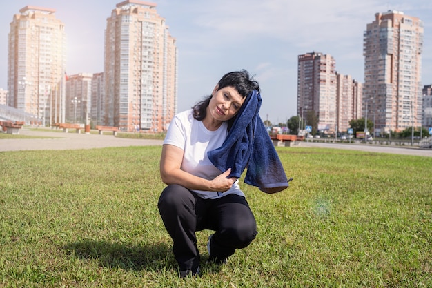 Mujer mayor secándose el sudor después de un duro entrenamiento al aire libre en el parque