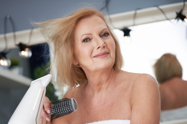 mujer mayor, secar el cabello, en el baño