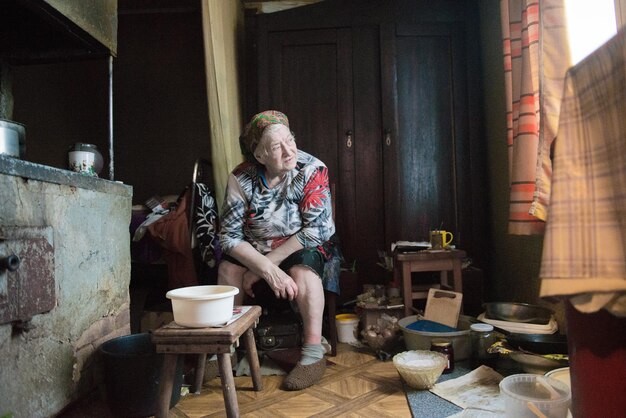 Foto una mujer mayor sentada en medio de utensilios en casa