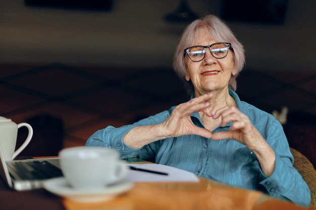 mujer mayor, sentado, en, un, café, con, un, taza de café, y, un, computadora portátil