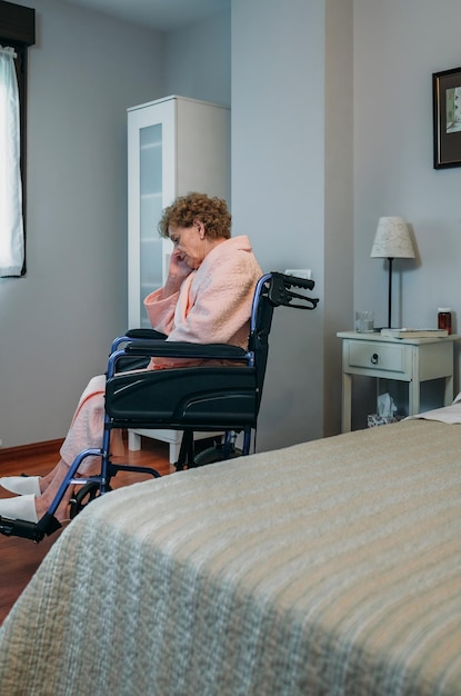 Mujer mayor en silla de ruedas sola en una habitación