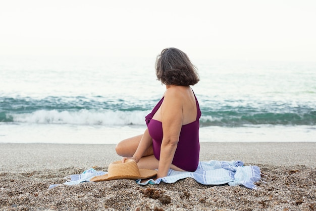 Mujer mayor con sombrero de paja disfrutando de su día en la playa