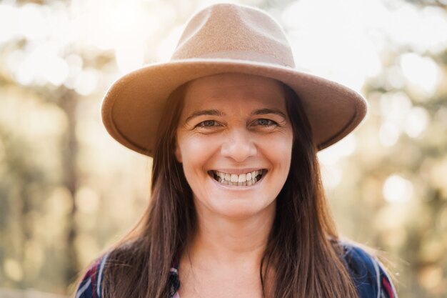 Mujer mayor sonriendo a la cámara al aire libre en el bosque - Centrarse en la cara