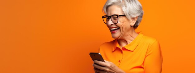 Foto una mujer mayor sonriendo y riendo con su teléfono contra un fondo de color